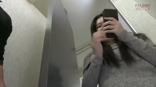 注视镜头 · 女性上半身特写 · 智能手机 · 室内走廊 · 灰色针织毛衣