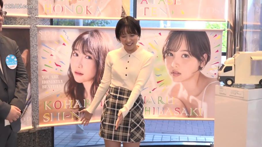 微笑 · 米白色针织长袖衫 · 活动现场 · 人物半身特写 · 宣传展板