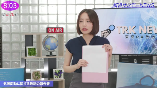 专注 · 电视台演播室 · 灰色职业长裤 · 主播上半身特写 · 新闻台背景 · 右下角显示TRK NEWS标识