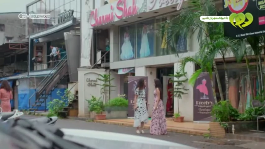 交谈 · 服装店门口 · 长裙 · 立式广告牌 · 背景有印度风格招牌
