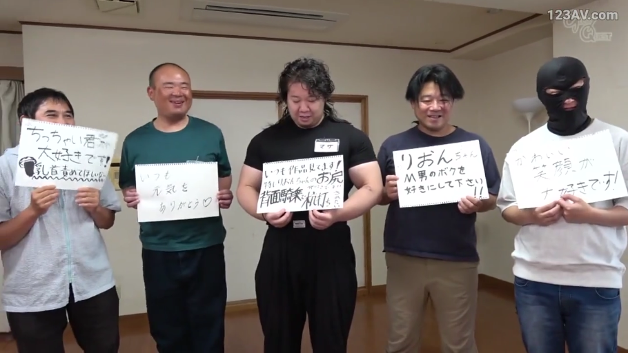 房间 · 兴奋 · 紧身黑色短袖 · 白色纸板 · 手持的文字板内容特写 · 纸板上写着日语愿望，内容涉及乳头刺激、后背位骑乘和M男调教等性暗示词汇