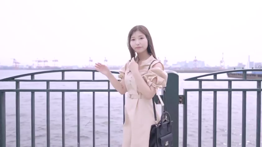 微笑 · 上半身特写 · 港口 · 黑色手提包 · 露肩设计 · 背景可见远处的起重机和水面