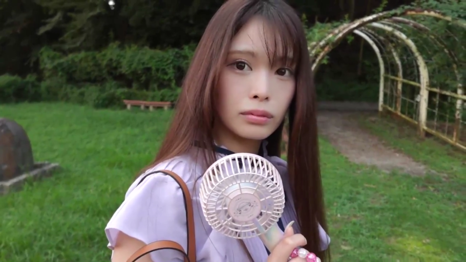 手持风扇特写 · 注视 · 绿地 · 浅紫色上衣 · 小型手持风扇