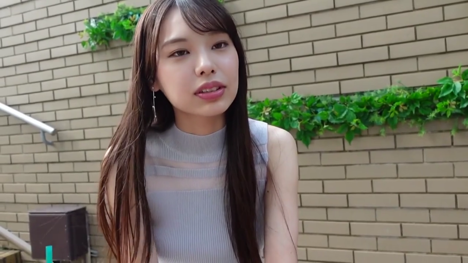 脸部特写 · 注视镜头 · 长发 · 正面坐姿 · 灰色无袖背心 · 耳饰 · 户外砖墙 · 自然表情