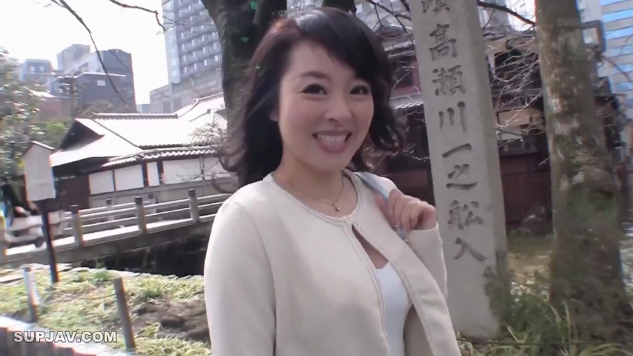 半身特写 · 熟女 · 对着镜头微笑 · 喜悦 · 户外街道 · 单肩包 · 侧身站立 · 米色开衫