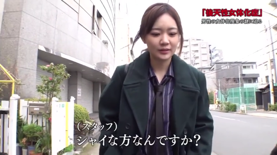 略显羞涩 · 街道 · 墨绿色大衣 · 人物面部特写 · 日文标题“后天性女性化症” · 无